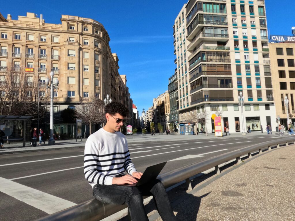 a man sitting on a bench using a laptop computer